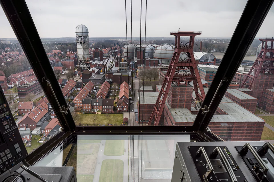 Blick aus einer Führerkanzel über eine Zeche und die Häuser einer Arbeitersiedlung